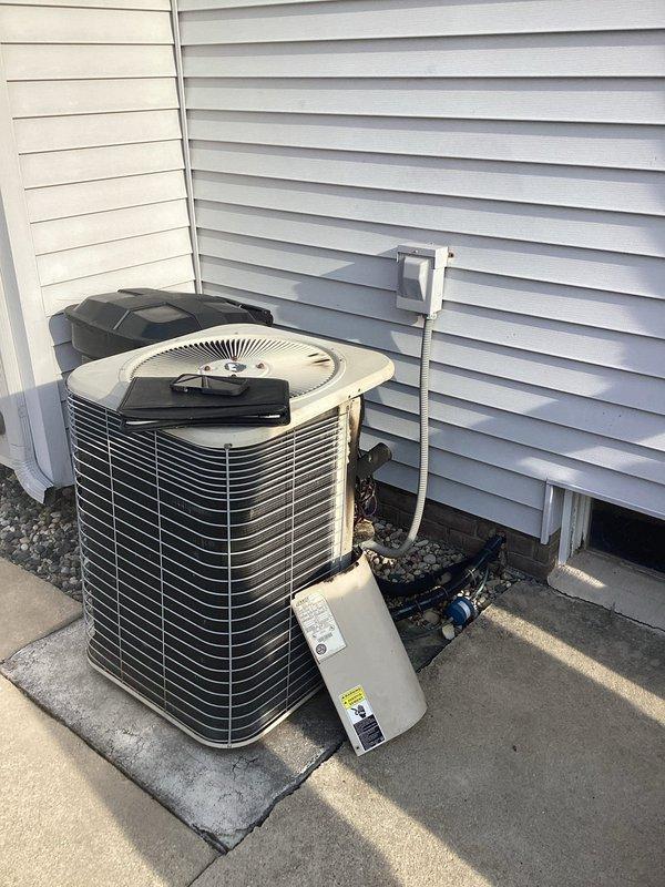 Conducted comprehensive assessment of existing HVAC system for replacement estimate. Outdoor air conditioning condenser unit evaluated and photographed, showing age-related wear on beige/tan cylindrical unit with horizontal fin configuration. Interior inspection revealed significant thermal damage to blower assembly, including visible charring, melted components, and deterioration around motor housing with damaged electrical wiring. Provided estimate for complete air conditioning replacement and potential furnace replacement based on observed equipment failure and safety concerns.