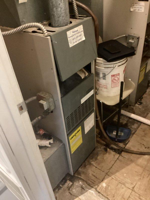 Conducted comprehensive site assessment for complete HVAC system and water heater replacement at commercial property with ground-level equipment installation. Evaluated existing Ariston brand water heater with blue control panel and standard plumbing connections including hot and cold water lines with brass valves and fittings. Assessed current furnace unit with metal paneling, flexible metal conduit connections, and associated ductwork. Documented all equipment specifications, manufacturer labels, and existing utility configurations including electrical wiring, PVC drainage lines, and mechanical room layout to provide accurate replacement estimate for full system upgrade.