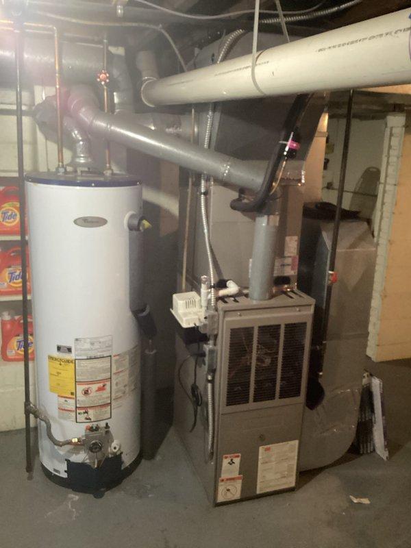 Conducted comprehensive assessment of existing residential HVAC system located in basement utility area for furnace replacement estimate. Evaluated current beige/tan furnace unit with front ventilation grille, documented equipment specifications, and photographed existing installation including adjacent water heater, ductwork configuration, refrigerant lines, and electrical connections. Assessed spatial constraints, existing duct system compatibility, and utility connections to provide accurate replacement recommendations for new furnace installation.