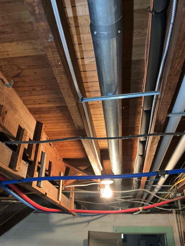Responded to no-cooling complaint on five-year-old air conditioning system that failed to operate following recent maintenance visit approximately one week prior. Upon arrival, confirmed unit would not energize despite homeowner attempts to cycle power at furnace. Performed diagnostic evaluation of system components, inspected electrical connections, and verified thermostat communication. Documented existing installation conditions in basement mechanical area showing ductwork, support structure, and related HVAC infrastructure. System restored to normal operation and cooling function verified before departure.