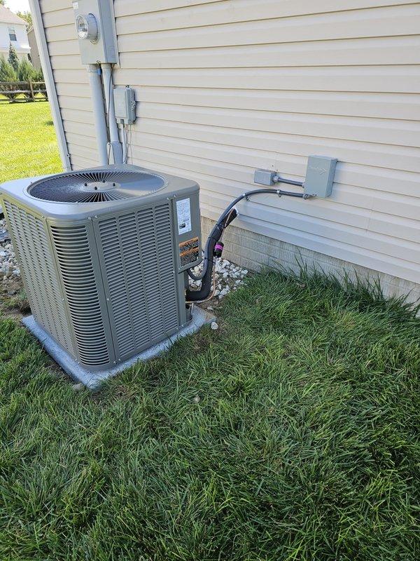 Completed full HVAC system installation including 80% AFUE upflow gas furnace with matching upflow cased evaporator coil per AHRI certification 215586564. Relocated outdoor Lennox condensing unit approximately 3 feet from electrical meter to optimize placement and clearances. Installed new level concrete equipment pad and positioned condenser on decorative rock bed for proper drainage and aesthetics.

Ran new 20-foot 3/4-inch refrigerant lineset from outdoor unit through exterior wall to indoor coil, properly insulated and secured to building. Installed new electrical disconnect box and flexible conduit whip at condensing unit with appropriate wire gauge per manufacturer specifications. Routed gray electrical conduit along exterior siding connecting to existing meter base and service panel.

Mounted new programmable thermostat at interior location for system control. Pressure tested refrigerant lines, evacuated system to proper micron level, and charged unit to manufacturer specificati