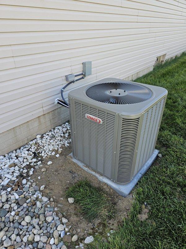 Completed full HVAC system installation including 80% AFUE upflow gas furnace with matching upflow cased evaporator coil per AHRI certification 215586564. Relocated outdoor Lennox condensing unit approximately 3 feet from electrical meter to optimize placement and clearances. Installed new level concrete equipment pad and positioned condenser on decorative rock bed for proper drainage and aesthetics.

Ran new 20-foot 3/4-inch refrigerant lineset from outdoor unit through exterior wall to indoor coil, properly insulated and secured to building. Installed new electrical disconnect box and flexible conduit whip at condensing unit with appropriate wire gauge per manufacturer specifications. Routed gray electrical conduit along exterior siding connecting to existing meter base and service panel.

Mounted new programmable thermostat at interior location for system control. Pressure tested refrigerant lines, evacuated system to proper micron level, and charged unit to manufacturer specificati