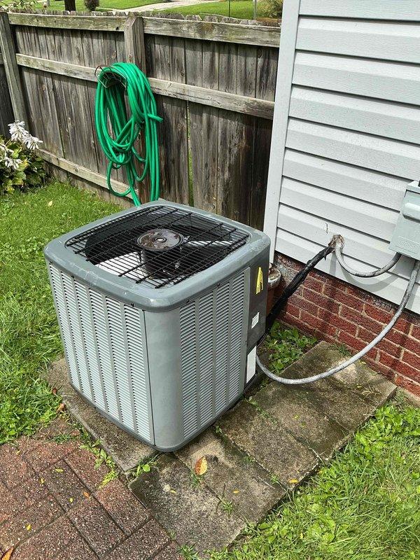 # HVAC Service Completed

Responded to service call for outdoor air conditioning unit displaying error code. Upon arrival, inspected 15-year-old residential AC system located on concrete pad in backyard area. Unit is a gray/silver condensing unit with vertical slats and black protective fan grille on top.

Performed comprehensive diagnostic evaluation of the system. Checked electrical connections at outdoor disconnect box mounted on house exterior. Inspected refrigerant lines, electrical conduit runs, and all external components for visible damage or wear. Verified proper unit positioning and clearances around equipment.

Assessed condenser coil condition through protective grille and examined fan motor operation. Tested system startup sequence and monitored for abnormal sounds or vibrations. Cleared error code and verified system returned to normal operating parameters. Unit cycling properly with no further fault codes detected.

Confirmed adequate airflow through condenser coils and 