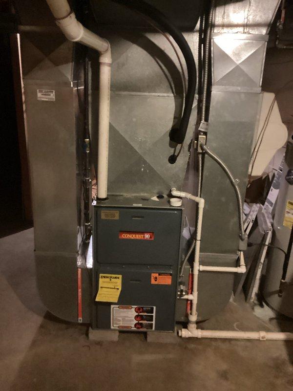 Completed comprehensive estimate for full HVAC system replacement at residential property. Evaluated existing outdoor condensing unit positioned against brick exterior wall near electrical meter and assessed indoor Conquest 80 furnace with connected air handler in basement utility area. Documented current system configuration including electrical disconnects, conduit runs, PVC venting, and ductwork connections to provide accurate replacement specifications and equipment sizing recommendations.
