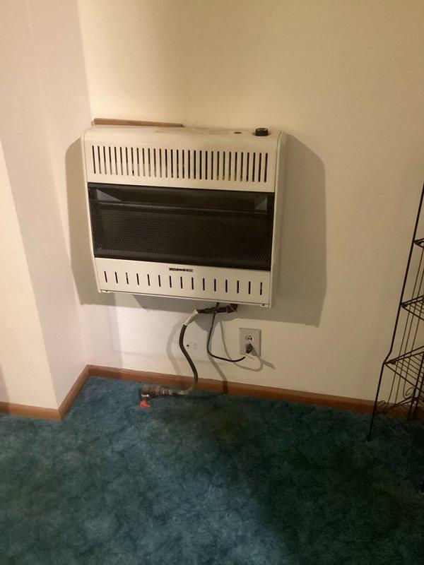 Completed estimate for replacement of existing wall-mounted vent-free space heater showing visible age and corrosion on components. Documented current unit condition with photos of heating system and corroded metal parts, evaluated gas line connections and wall mounting configuration, and provided recommendations for new equipment installation to ensure safe and efficient heating operation.