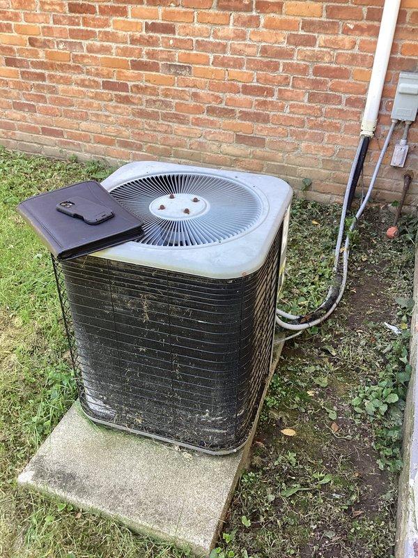 Conducted comprehensive HVAC system evaluation for furnace and air conditioning replacement estimate. Inspected existing Lennox furnace installation in interior utility closet and outdoor condenser unit positioned on concrete pad adjacent to building exterior. Assessed current equipment condition, noting weathered condenser with accumulated debris on fins and grille, and documented existing PVC condensate drainage routing and refrigerant line configuration. Photographed both units to document pre-replacement condition and discussed available equipment upgrade options and current promotional offerings with homeowner.
