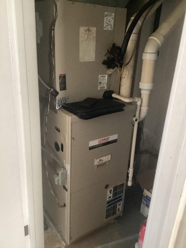 Conducted comprehensive HVAC system evaluation for furnace and air conditioning replacement estimate. Inspected existing Lennox furnace installation in interior utility closet and outdoor condenser unit positioned on concrete pad adjacent to building exterior. Assessed current equipment condition, noting weathered condenser with accumulated debris on fins and grille, and documented existing PVC condensate drainage routing and refrigerant line configuration. Photographed both units to document pre-replacement condition and discussed available equipment upgrade options and current promotional offerings with homeowner.