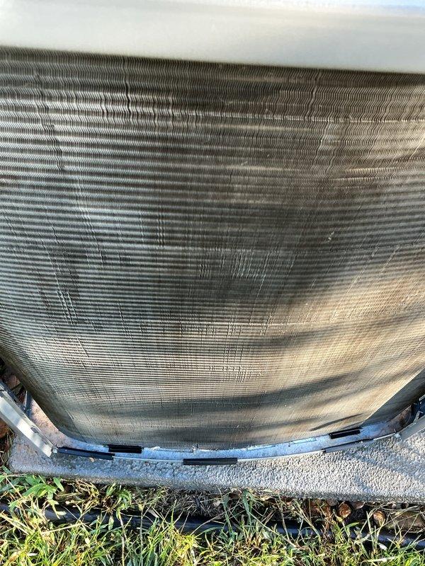 Completed standard AC tune-up on 4-year-old condensing unit. Inspected condenser coil and noted moderate dirt accumulation and discoloration in central sections, indicating need for future cleaning to maintain optimal heat transfer efficiency. Verified unit operational status, checked fan guard assembly, and confirmed equipment is functioning on level concrete pad with adequate clearance.