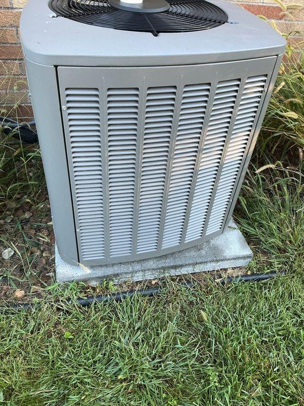 Completed standard AC tune-up on 4-year-old condensing unit. Inspected condenser coil and noted moderate dirt accumulation and discoloration in central sections, indicating need for future cleaning to maintain optimal heat transfer efficiency. Verified unit operational status, checked fan guard assembly, and confirmed equipment is functioning on level concrete pad with adequate clearance.