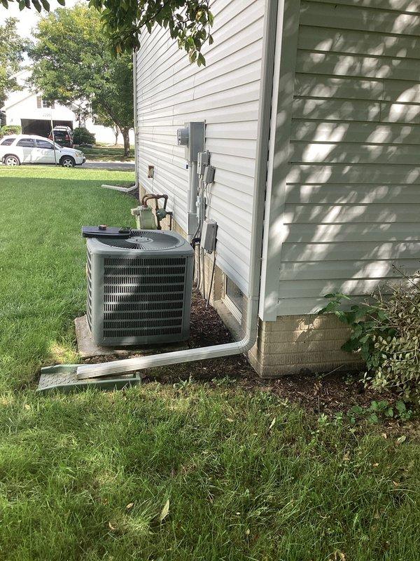 Completed comprehensive estimate for full HVAC system replacement at residential property. Evaluated existing Amana furnace installation located in basement utility area with interconnected air handler and evaporator coil assembly. Assessed current system configuration including white PVC condensate drainage piping, ductwork connections, and ventilation components within confined mechanical space. Inspected outdoor condensing unit positioned on concrete pad against home exterior with proper clearances from structure. Unit currently installed in mulched area adjacent to white vinyl siding with electrical service panel and meter mounted above on exterior wall. Documented complete system layout including refrigerant line set routing, electrical connections, and overall equipment condition. Photographed indoor furnace assembly showing vertical installation with top-mounted coil configuration and multiple PVC pipe connections for combustion air and condensate removal. Captured outdoor unit 