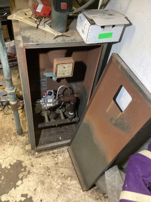 Completed comprehensive assessment of existing boiler system for replacement estimate. Inspected aging boiler unit housed in metal cabinet enclosure showing significant corrosion and wear on exterior surfaces. Evaluated gas valve assembly, burner mechanism, and associated pressure gauges within cabinet. Documented condition of existing copper supply and return piping with visible oxidation, red zone valves with pressure indicators, and horizontal ductwork passing through utility room. Photographed all mechanical components and infrastructure to provide detailed replacement specifications. Provided customer with complete estimate for new boiler installation including removal of existing equipment and integration with current piping system.