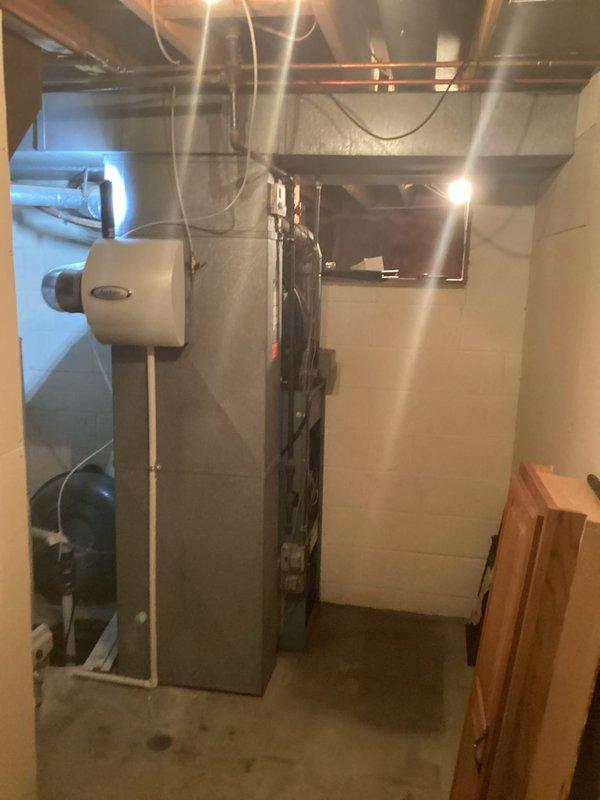Conducted comprehensive assessment of existing HVAC system and infrastructure in basement mechanical room for equipment replacement estimate. Documented current furnace installation, water heater configuration, and complete ductwork layout including aged insulated supply and return ducts with visible wear and dust accumulation. Evaluated existing system components, mounting brackets, copper piping runs, electrical conduit routing, and mechanical room accessibility for replacement equipment installation planning.