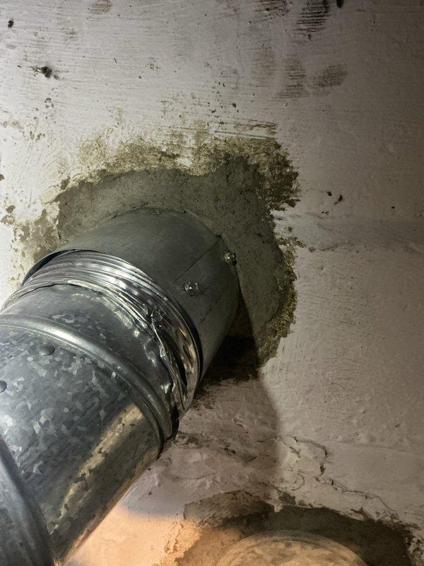 Completed inspection correction work to address code compliance and safety issues. Installed proper sleeve on masonry wall penetration for refrigerant line set, replacing inadequate caulking application. Reconnected venting to chimney liner to eliminate gap that was allowing carbon monoxide to leak into living space, restoring safe operation of heating system.