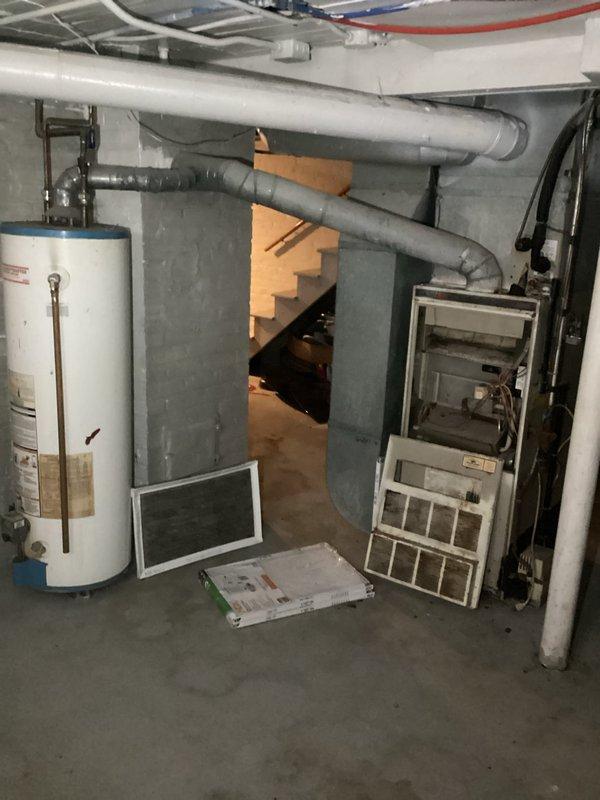 Completed furnace replacement estimate for residential basement installation. Assessed existing aging furnace unit with heavily soiled filters and evaluated current ductwork configuration, including horizontal sheet metal supply ducts and PVC venting system. Documented equipment layout, clearances, and existing infrastructure including water heater proximity and electrical connections to provide comprehensive replacement options and sizing recommendations.