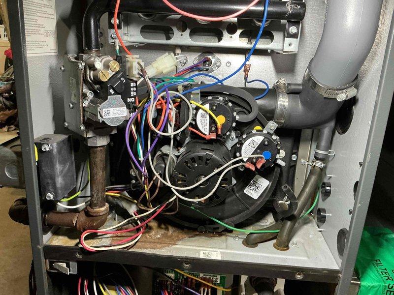 Responded to service call for water accumulation around furnace base and unusual odor reported by occupant. Performed comprehensive inspection of furnace interior components, including blower assembly, heat exchanger, condensate drainage system, and burner compartment. Examined all electrical connections, circuit boards, and wiring harnesses for signs of moisture intrusion or thermal damage. Inspected evaporator coil, condensate drain lines, and trap for blockages or leaks that could cause water pooling. Verified proper operation of inducer motor assembly and checked flue piping for condensation issues. Documented equipment condition with detailed photographs showing internal components, motor assemblies, gas valve connections, and all visible mechanical systems for service records and future reference.