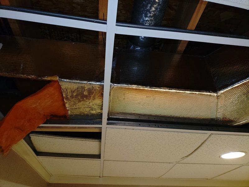 Responded to water leak affecting HVAC ductwork caused by disconnected waterline from Aprilaire humidifier valve. Inspected ceiling cavity and ductwork system, documenting water damage to flexible duct insulation and surrounding areas. Removed ceiling tiles to assess extent of moisture infiltration and identify source of odor reported by customer. Photographed affected ductwork sections showing water-damaged insulation material and compromised duct integrity requiring replacement to prevent mold growth and maintain indoor air quality.