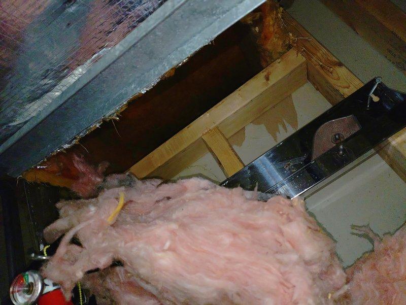 Responded to water leak affecting HVAC ductwork caused by disconnected waterline from Aprilaire humidifier valve. Inspected ceiling cavity and ductwork system, documenting water damage to flexible duct insulation and surrounding areas. Removed ceiling tiles to assess extent of moisture infiltration and identify source of odor reported by customer. Photographed affected ductwork sections showing water-damaged insulation material and compromised duct integrity requiring replacement to prevent mold growth and maintain indoor air quality.