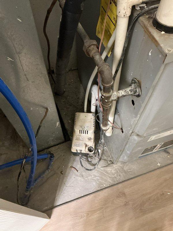 Responded to service call for water leakage from 22-year-old air conditioning system. Upon arrival, accessed property and performed diagnostic inspection of outdoor condensing unit and indoor air handler components. Inspected refrigerant lines, condensate drain system, and mechanical connections at both exterior unit location and basement installation area. Documented equipment condition showing age-related wear on piping and system components. Confirmed unit operation and identified source of water leakage for repair recommendations.