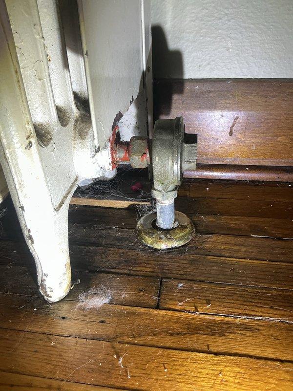 Responded to radiator leak complaint from previous winter season. Upon inspection, identified failed outlet valve as source of substantial water leakage. Documented condition of radiator outlet valve assembly and surrounding area showing evidence of significant water discharge and deterioration to adjacent surfaces and flooring.