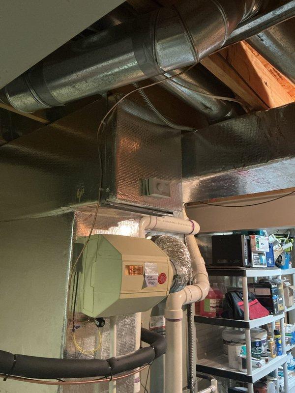 # HVAC Ductwork Installation

Completed installation of metallic rigid ductwork system in utility room with horizontal runs across exposed ceiling joists. Integrated rectangular air handler with filter box into main duct trunk line and connected flexible insulated ducting to establish proper airflow distribution. Installed cream-colored HVAC unit with PVC condensate drainage lines featuring multiple elbows and straight sections for proper pitch and drainage. Extended ductwork system into adjacent garage space, routing metal ducts along ceiling structure to provide conditioned air throughout both areas. All ductwork secured with appropriate hangers and straps to structural members, seams sealed, and connections banded per code requirements. System tested for proper airflow and verified all connections are secure and leak-free.