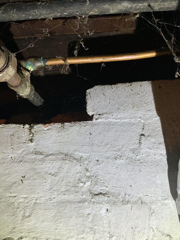 # Water Heater Replacement Estimate

Conducted on-site assessment of existing water heater installation located in basement utility area. Inspected current unit, a cylindrical tank-style water heater with visible manufacturer labeling and standard plumbing connections including shutoff valve and supply lines. Evaluated existing copper piping infrastructure, noting patina consistent with age and normal oxidation. Examined installation environment including overhead ductwork, structural joists, and concrete foundation to determine accessibility and any potential complications for replacement work.

Documented water heater configuration with red-wheeled gas shutoff valve, top-mounted connections, and proximity to HVAC ductwork system. Assessed clearance requirements and existing venting arrangements. Photographed current installation showing PVC and metal pipe connections, concrete floor mounting surface, and spatial constraints within mechanical room. Noted crawl space conditions includi