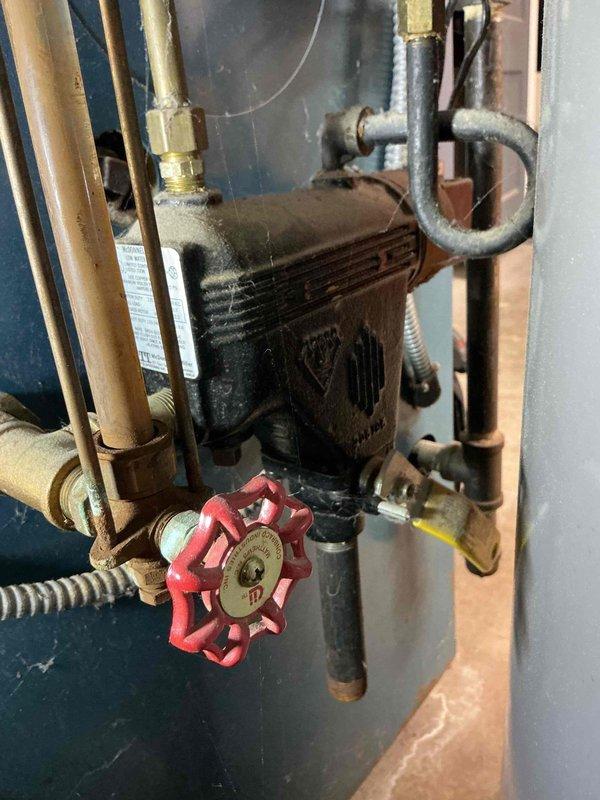 Responded to service call for leaking sight glass on 32-year-old hydronic heating system. Upon inspection, identified leaking glass tube assembly on boiler requiring immediate attention to prevent water damage. Discussed system age and replacement options with homeowner given the advanced age of the equipment and potential for additional component failures. Placed collection bucket beneath leak as temporary measure and documented existing conditions including aged copper piping, circulation pump, and pressure gauge assembly showing signs of corrosion and wear consistent with three decades of operation.