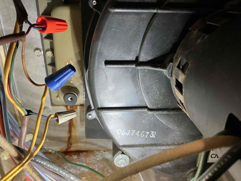 Responded to reported water leak originating from furnace condensation system. Upon inspection, identified active leaking from condensate collection box located behind the inducer blower assembly. Visual examination revealed significant rust and corrosion on metal mounting brackets and surrounding components, indicating prolonged moisture exposure. Inspected blower housing, electrical connections, and condensate drainage system including white PVC drain lines. Documented existing conditions with photographs showing corroded hardware, wire connections with properly secured wire nuts, and overall system configuration. Heavy dust accumulation and oxidation present on metal surfaces throughout the affected area confirmed chronic condensation issues requiring attention to prevent further component deterioration and ensure proper drainage function.