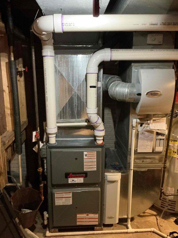 Completed comprehensive tune-up on 12-year-old residential gas furnace system. Inspected air filter showing moderate dust accumulation, verified proper installation within metal frame housing, and examined all accessible HVAC components including humidifier unit and PVC venting system. All equipment confirmed operational with no immediate service concerns identified.