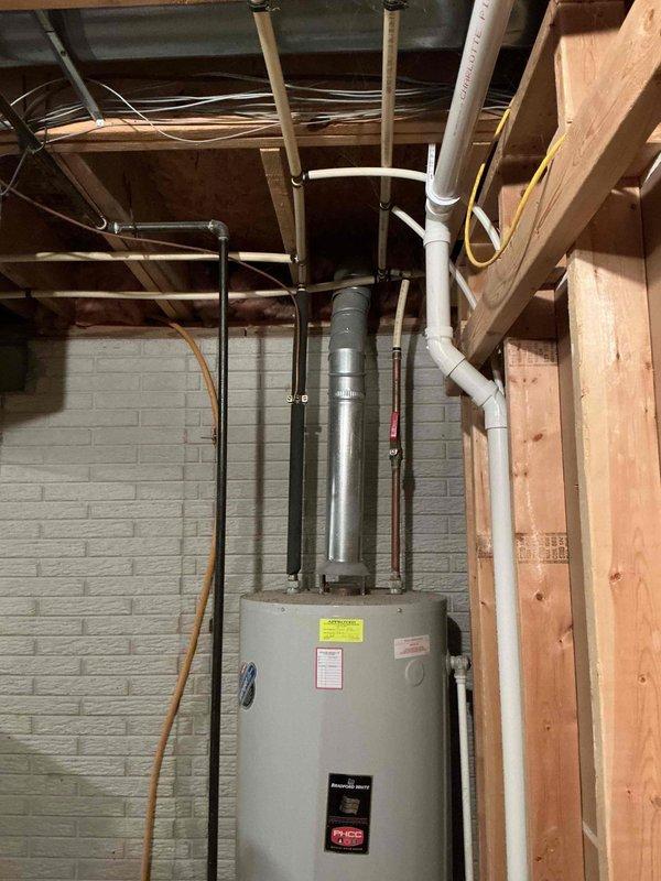 Provided estimate for replacement of existing natural gas water heater with new 65-gallon, 65,000 BTU unit. Inspected current water heater installation in basement utility area, noting standard venting configuration with PVC and metallic ductwork, copper and PVC supply lines, and gas connection at base of unit. Documented existing equipment specifications and installation conditions to prepare accurate replacement proposal.