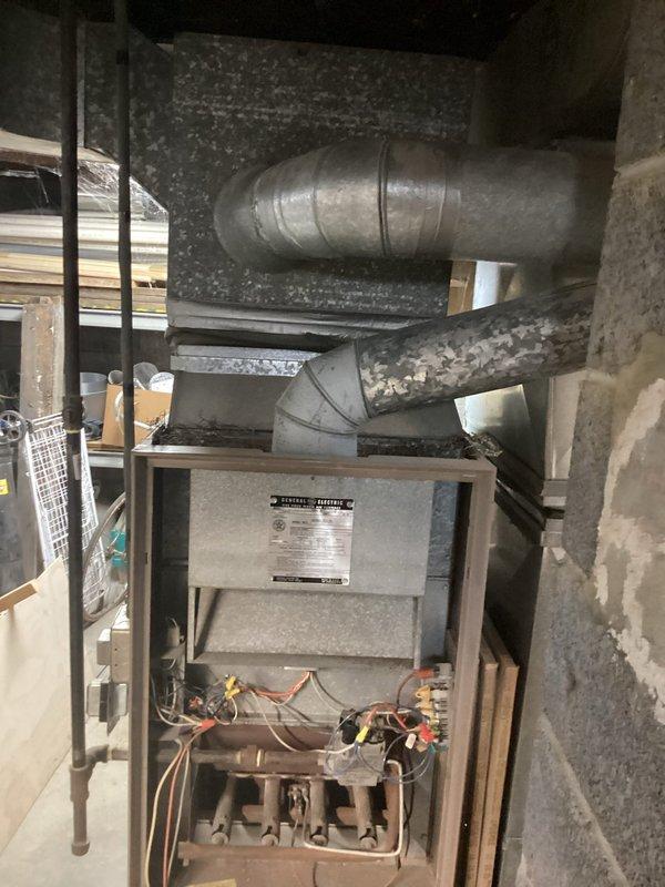 Completed comprehensive estimate for furnace replacement in residential basement utility area. Evaluated existing gas furnace unit with beige/gray metal cabinet housing, assessed current ductwork configuration including horizontal trunk line and elbow connections, and documented all mechanical connections including copper refrigerant lines, gas piping, electrical wiring, and venting requirements. Provided customer with replacement options and specifications for new high-efficiency furnace system compatible with existing duct infrastructure and clearance requirements adjacent to masonry chimney and water heater.