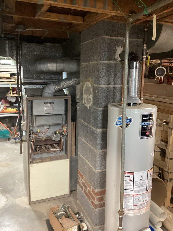 Completed comprehensive estimate for furnace replacement in residential basement utility area. Evaluated existing gas furnace unit with beige/gray metal cabinet housing, assessed current ductwork configuration including horizontal trunk line and elbow connections, and documented all mechanical connections including copper refrigerant lines, gas piping, electrical wiring, and venting requirements. Provided customer with replacement options and specifications for new high-efficiency furnace system compatible with existing duct infrastructure and clearance requirements adjacent to masonry chimney and water heater.