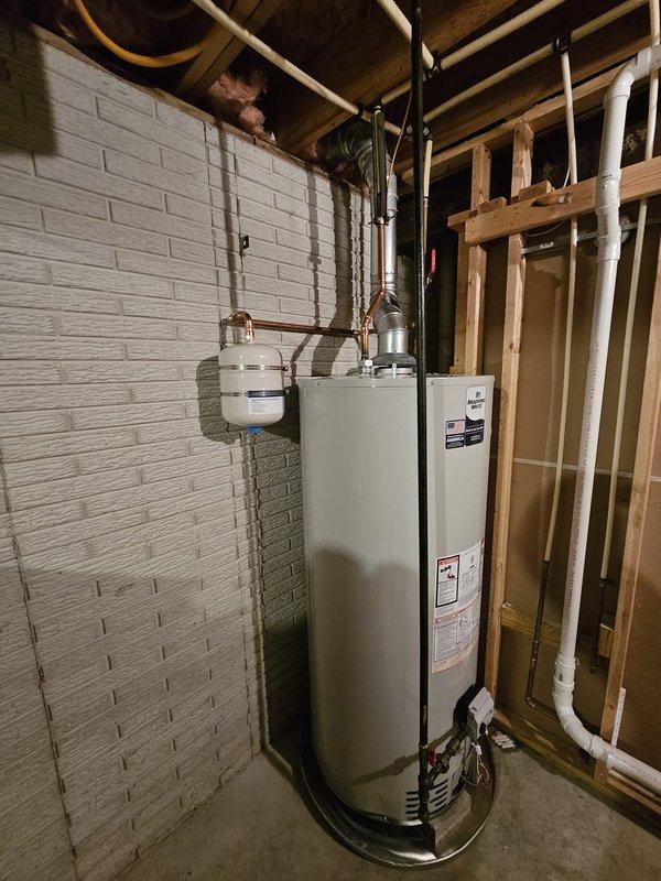 Installed 75-gallon natural gas water heater in basement utility area with proper code compliance upgrades. Added thermal expansion tank with wall-mounted bracket, installed drain pan with 10 feet of PVC piping routed to floor drain, and adjusted flue positioning to maintain minimum 1-inch clearance from PEX supply lines. Corrected gas piping configuration by installing tee fitting and shut-off valve to properly accommodate Ward flex connector off sediment trap, ensuring safe and compliant fuel gas delivery to unit.