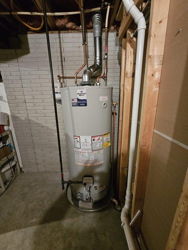 Installed 75-gallon natural gas water heater in basement utility area with proper code compliance upgrades. Added thermal expansion tank with wall-mounted bracket, installed drain pan with 10 feet of PVC piping routed to floor drain, and adjusted flue positioning to maintain minimum 1-inch clearance from PEX supply lines. Corrected gas piping configuration by installing tee fitting and shut-off valve to properly accommodate Ward flex connector off sediment trap, ensuring safe and compliant fuel gas delivery to unit.