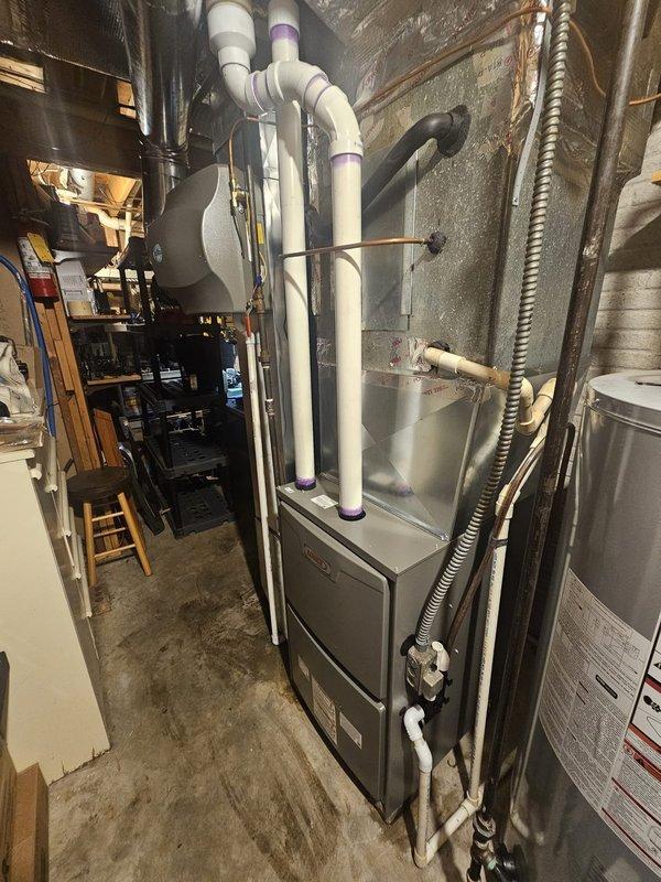 Completed installation of a 90% AFUE two-stage variable speed furnace in basement utility area. Replaced existing metal return drop to accommodate new equipment specifications. Installed 17-gallon whole-home humidifier integrated with the HVAC system. Established new gas line connections and electrical wiring to code specifications for safe furnace operation. Mounted and programmed new thermostat for two-stage heating control. Installed humidistat below main thermostat for independent humidity management. Connected white PVC exhaust and intake venting system, properly securing all condensate drainage lines. Verified all connections, tested system operation across both heating stages, and confirmed proper variable speed blower functionality. Equipment is operational and performing to manufacturer specifications.