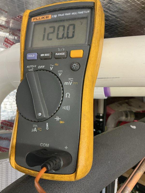 Completed routine heating maintenance visit on a 3-year-old system. Performed electrical diagnostics using multimeter, confirmed proper voltage readings at 120V, and inspected HVAC equipment including associated plumbing connections and water heater components in the utility area.