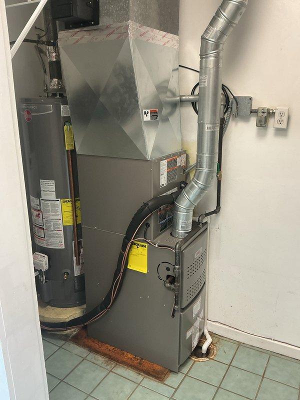 # Complete HVAC System Installation

Completed full residential HVAC system installation featuring a Lennox Merit Series furnace with 80% AFUE rating, single-stage heating, standard torque blower motor, and stainless steel heat exchanger. Installed accompanying 13 SEER single-stage air conditioning unit with new refrigerant line set and equipment pad. Upgraded electrical infrastructure including new disconnect box and supply whip to meet current code requirements. Mounted new programmable thermostat for enhanced climate control and energy management. System positioned in interior mechanical room alongside existing water heater, with proper clearances maintained for service access. Exterior condensing unit installed on new equipment pad with appropriate drainage considerations. All ductwork connections secured to pyramid-style plenum with proper sealing. PVC condensate drain line routed through exterior brick wall with weatherproof boot installation at penetration point. Verified all el