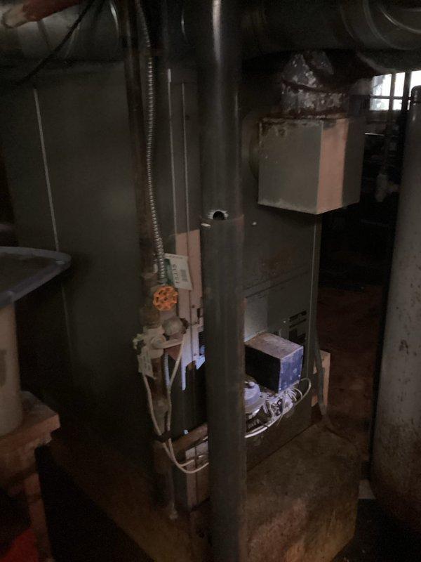 Conducted comprehensive assessment of existing residential heating system in preparation for furnace replacement estimate. Evaluated current furnace unit, an older model gas-fired system showing signs of age and wear, along with associated ductwork, venting, and utility connections. Documented existing equipment configuration including flexible ductwork distribution, gas line connections with shutoff valve, PVC condensate drainage, and electrical service. Assessed installation space constraints in basement utility area and measured clearances for new equipment placement. Photographed current system components, connections, and surrounding mechanical room layout to develop accurate replacement specifications and ensure proper sizing for new furnace installation.