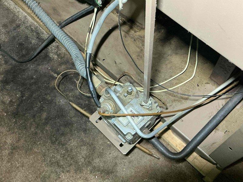 # HVAC Service Call - Empire Space Heater No Heat

Responded to service call for 30-year-old Empire space heater with non-functional pilot safety button. Upon inspection, found the manual reset button (thermocouple safety control) had mechanically failed, preventing pilot flame ignition and system operation. 

Performed comprehensive system evaluation as requested. Inspected gas supply lines, electrical connections, and mounting hardware. Noted significant corrosion and oxidation on copper components and valve assemblies, consistent with three decades of operation in basement installation environment. White and blue-green mineral deposits observed on copper surfaces indicate moisture exposure over extended period.

Examined thermocouple assembly, gas control valve, and pilot orifice. Verified integrity of flexible gas connector and junction box connections. Assessed condition of electrical conduit routing and wire management systems. All mounting brackets and hardware showed age-approp