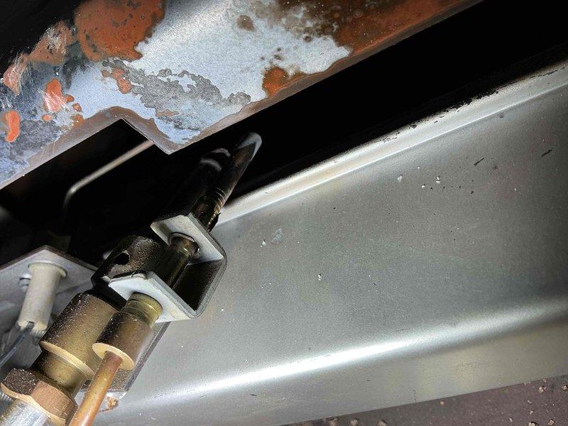 # HVAC Service Call - Empire Space Heater No Heat

Responded to service call for 30-year-old Empire space heater with non-functional pilot safety button. Upon inspection, found the manual reset button (thermocouple safety control) had mechanically failed, preventing pilot flame ignition and system operation. 

Performed comprehensive system evaluation as requested. Inspected gas supply lines, electrical connections, and mounting hardware. Noted significant corrosion and oxidation on copper components and valve assemblies, consistent with three decades of operation in basement installation environment. White and blue-green mineral deposits observed on copper surfaces indicate moisture exposure over extended period.

Examined thermocouple assembly, gas control valve, and pilot orifice. Verified integrity of flexible gas connector and junction box connections. Assessed condition of electrical conduit routing and wire management systems. All mounting brackets and hardware showed age-approp