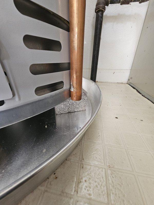 Responded to callback for T&P drain pipe obstruction. Upon arrival, found brick material positioned too close to the copper relief drain line at the water heater base, creating potential drainage interference. Removed and relocated the brick support material away from the vertical copper pipe to ensure unobstructed drainage path for temperature and pressure relief valve discharge. Verified proper clearance around drain pipe and confirmed drain pan accessibility. Installation now meets code requirements for T&P valve drainage with adequate clearance maintained around all plumbing components.