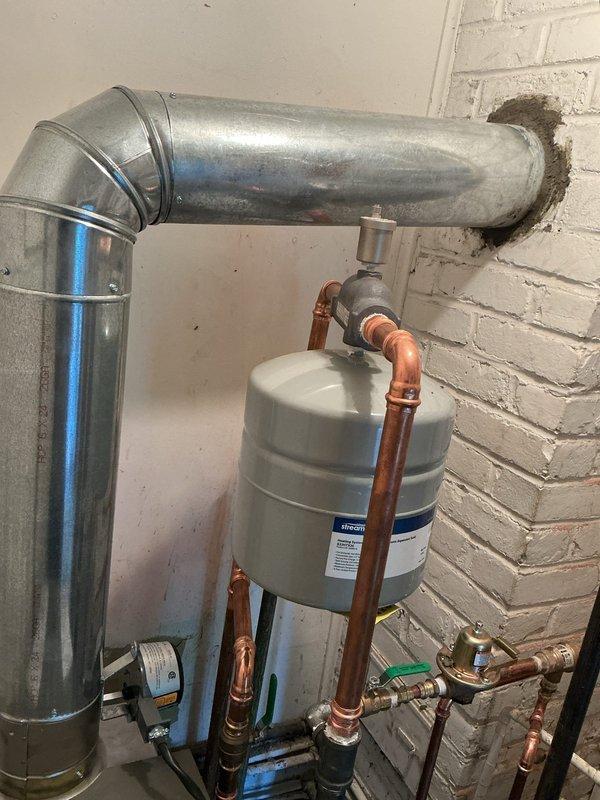 Installed Lennox 120,000 BTU floor mount boiler system in basement utility area. Installation included complete setup of boiler unit with associated copper supply and return piping, expansion tank mounting, pressure relief components, and metallic vent pipe system with proper exhaust configuration. All connections secured with appropriate brass fittings, shutoff valves installed for system isolation, and pressure regulation devices integrated per manufacturer specifications. System tested and confirmed operational upon completion.