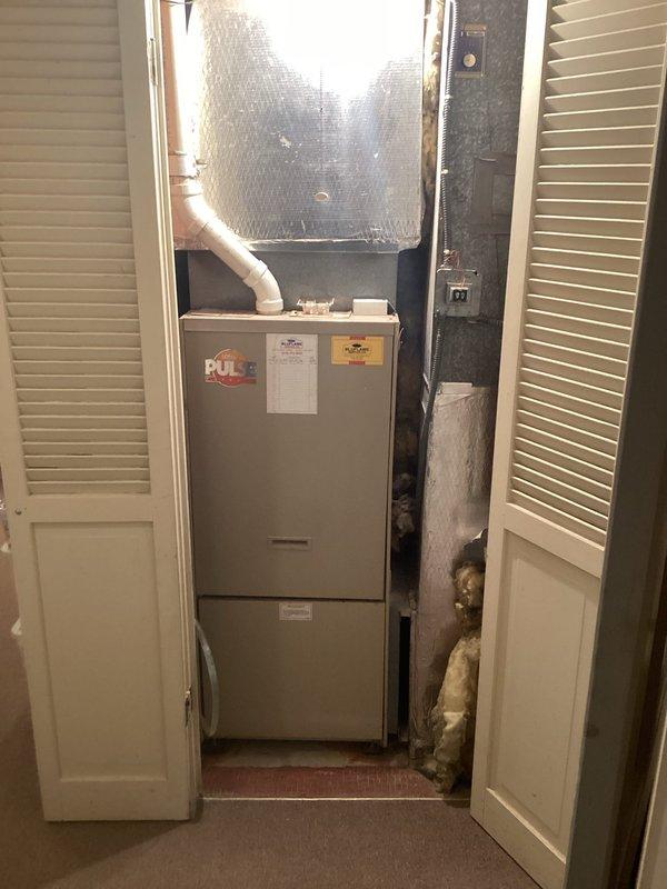 Completed comprehensive assessment of existing residential forced-air heating system located in interior utility closet. Documented current furnace unit configuration, including existing evaporator coil assembly with reflective insulation jacket, PVC condensate drainage system, and flexible duct connections to supply plenum. Evaluated equipment age, condition, and operational efficiency. Photographed installation layout showing vertical furnace positioning, electrical service panel location, available clearances, and existing ductwork routing. Provided detailed replacement estimate for new high-efficiency heating system with proper sizing calculations and equipment specifications.