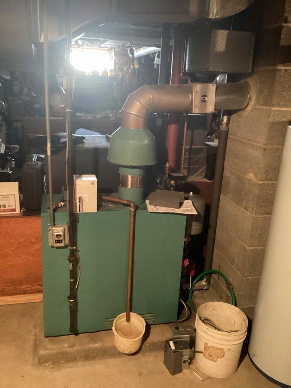 Completed comprehensive assessment of existing boiler system in basement mechanical room for equipment replacement quote. Documented current turquoise-colored hydronic heating unit with copper piping distribution, associated controls, and ancillary components including proximity to domestic water heater. Photographed installation conditions, clearances, existing piping configurations, and mechanical room layout to develop accurate replacement specifications and scope of work for customer approval.