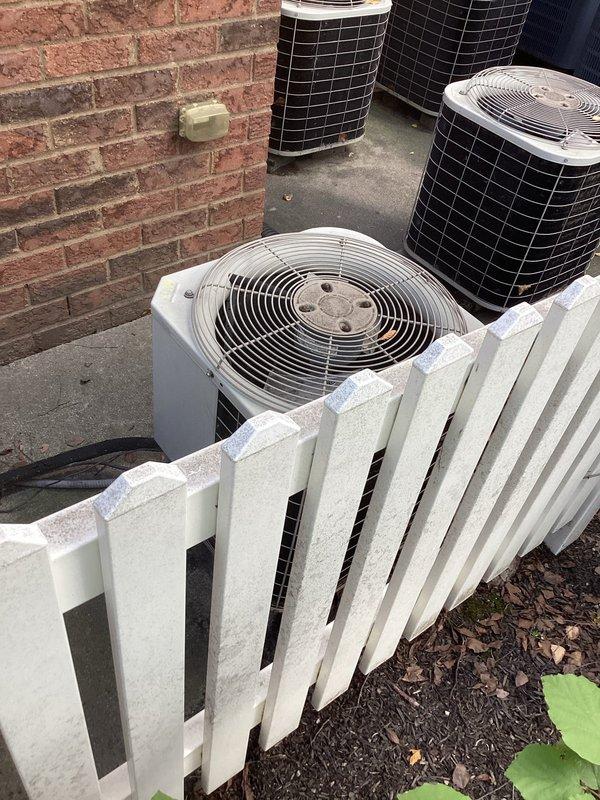 Conducted commercial mini-split system estimate at brick building exterior with existing HVAC equipment. Documented current installation conditions including three wall-mounted electrical junction boxes with conduit connections, existing condenser unit placement on concrete pad, and available service access behind perimeter fencing with mulch landscaping. Assessed wall penetration requirements and evaluated optimal placement for additional mini-split outdoor units adjacent to existing equipment array on concrete mounting surface.