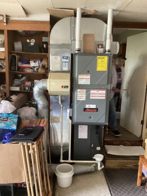 Conducted comprehensive evaluation of existing HVAC system for complete replacement of furnace and air conditioning unit. Assessed current basement-installed furnace with existing ductwork configuration, PVC venting system, and connected humidifier component to determine replacement specifications. Evaluated outdoor condenser unit positioned against exterior brick wall, including electrical disconnect box and refrigerant line routing. Documented equipment specifications, system layout, and installation requirements through detailed photography to provide accurate replacement estimate for complete heating and cooling system upgrade.
