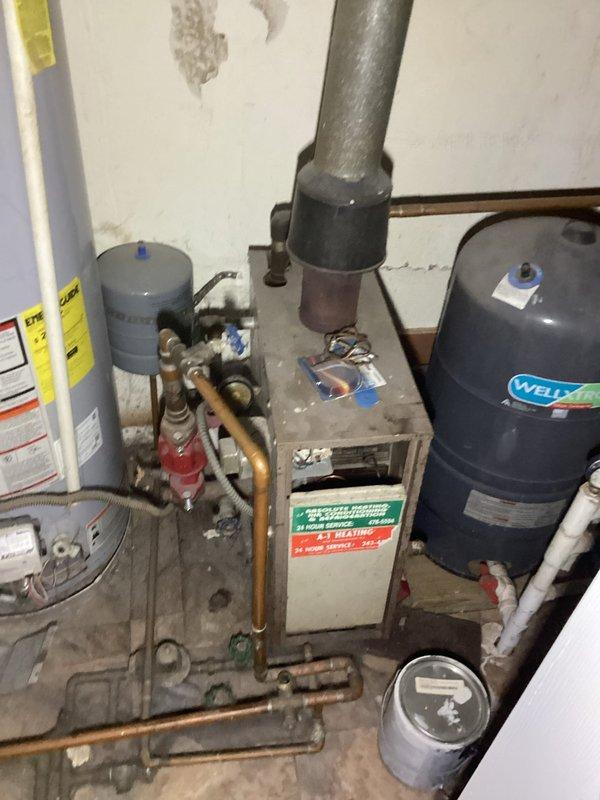 Completed finalization of HVAC replacement estimate with comprehensive photographic documentation of existing mechanical systems. Inspection revealed aging water pressure tank, water heater, and heating equipment in utility space requiring assessment for replacement specifications. Documented current equipment configuration including Well-X-Trol pressure tank, plumbing connections with copper and PVC piping, expansion tanks, and associated valve assemblies to provide accurate scope of work for proposed system replacement.