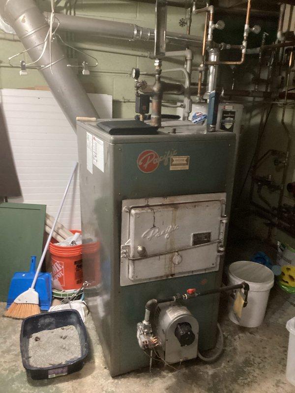 Conducted on-site assessment of existing residential boiler system in basement mechanical room to provide replacement estimate. The current unit is an older gray-green boiler with visible age-related wear, connected to copper piping distribution system and integrated with existing water heater. Evaluated the complete heating system infrastructure including supply and return piping, zone valves, circulation components, and venting requirements. Documented equipment specifications, spatial constraints, and existing plumbing configuration to determine appropriate replacement unit sizing and installation requirements. Photographed current installation to support equipment selection and project planning for the proposed boiler replacement.