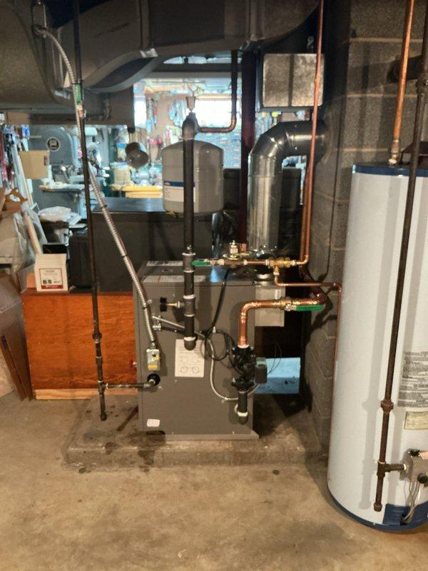 Completed residential boiler installation in basement mechanical room. New boiler unit was mounted on concrete pad with proper copper piping connections, green-handled isolation valves, and distribution lines routed to existing heating zones. All soldered joints were completed to code specifications, pressure tested, and system was commissioned for operational use alongside existing water heater.