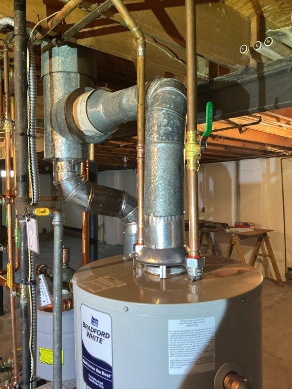 Completed installation of a 40-gallon slim Bradford White water heater in basement utility area. Connected all supply and discharge plumbing lines with copper piping, installed required shut-off valves, and integrated ventilation ductwork to existing HVAC system. Installation included proper venting configuration, safety valve installation, and verification of all connections for secure operation.
