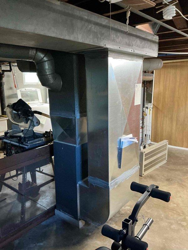 Performed a seasonal tune-up and inspection on a gas furnace, including a review of the flue venting connection, ductwork, and plenum seams, with foil-taped joints confirmed intact. Inspected surrounding equipment area and documented system condition; noted damp staining on the concrete floor near the furnace base and ductwork, and recommended monitoring for moisture or condensate sources.